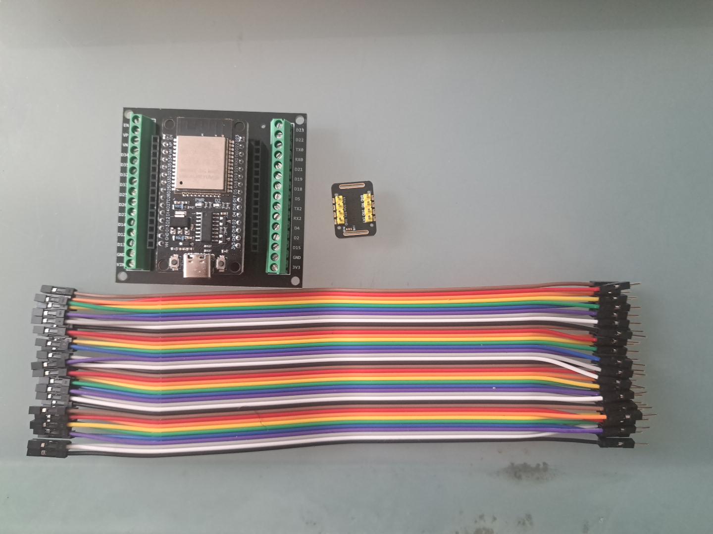 ESP32 breakout board beside a small MAX30102 sensor board and jumper wires